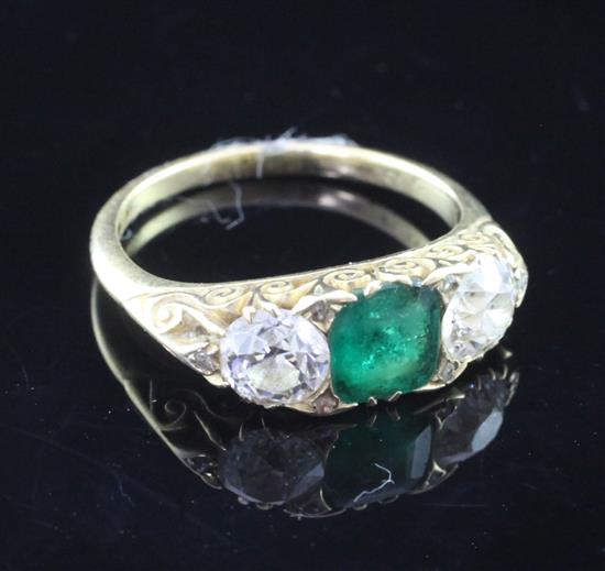 An 18ct gold and three stone emerald and diamond ring, size N.